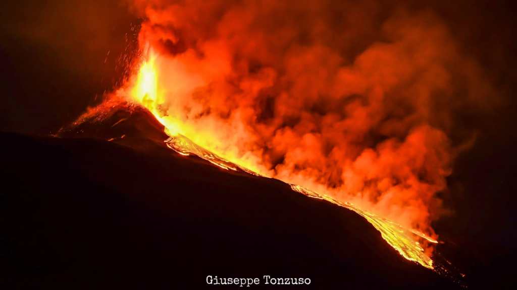 Figura 3 - Da un punto d’osservazione molto panoramico posto sull’orlo meridionale della Valle del Bove, Monte Zoccolaro, un gruppo di studenti universitari sta seguendo l’attività parossistica del 20 febbraio 2021 al Cratere di Sud-Est. Si nota la colata di lava in discesa verso la parte centrale della Valle del Bove. Foto di Giuseppe Tonzuso.