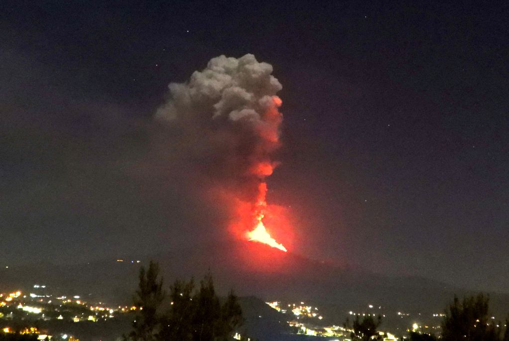 Figura 6 – Fontane di lava alte circa 300 m e colonna eruttiva iniziale che si alza circa 2 km sopra la vetta dell’Etna, verso le ore 21.00 del 24 febbraio 2021. La vista è da Trecastagni, sul versante sud-sud orientale del vulcano.