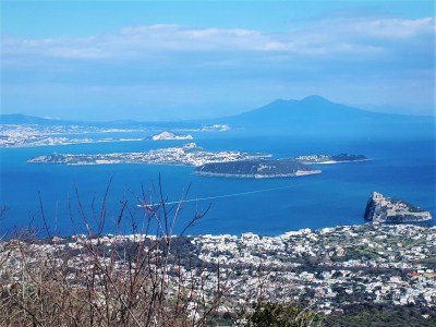 Panoramica a volo d’uccello dei vulcani napoletani dall’isola d’Ischia. In primo piano, sulla destra, il castello Aragonese di Ischia, in secondo piano Procida con l’isolotto di Vivara, i Campi Flegrei con Capo Miseno e, in fondo, il Somma Vesuvio. Fotografia di Sandro de Vita