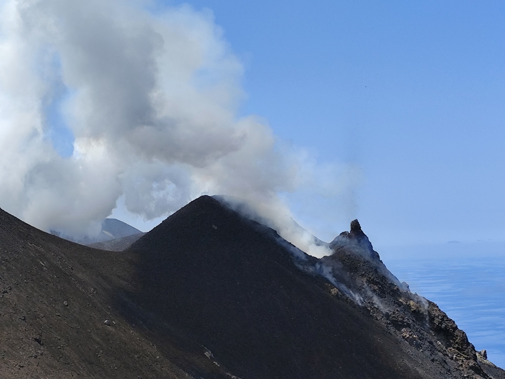 Figura 1 - Sulla destra si osserva un hornito, piccolo conetto subverticale formato dall’accumulo di scorie semifuse, sul bordo del cono di scorie più grande, cresciuto nel cratere di nordest della terrazza craterica di Stromboli (fotografia di Gianfilippo De Astis, fine maggio 2024).