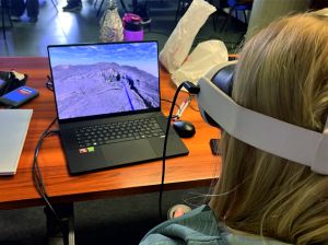 Figura 3 - Una corsista sta testando la realtà virtuale immersiva con computer e visore, sorvolando la fessura eruttiva che ha alimentato la colata lavica di Agosto 2025.